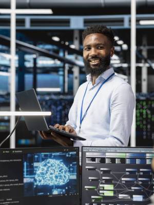 Cheerful man in server hub facility using artificial intelligence to perform demanding computing tasks. Jolly admin in data center uses AI technology for machine learning workloads